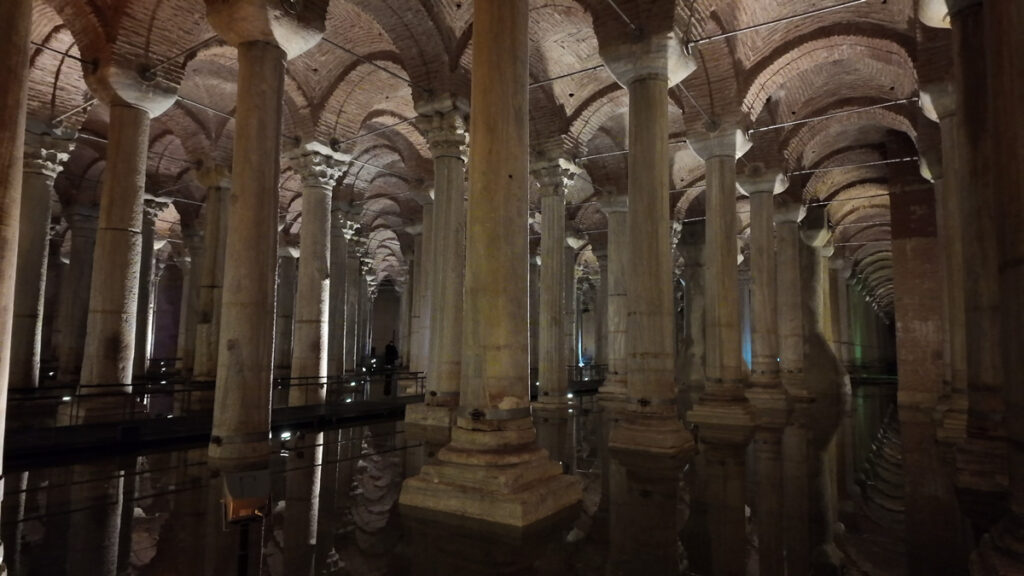 A wide view of the Basilica Cistern’s central column corridor in Istanbul, with rows of marble columns reflected in the water under arched brick ceilings.