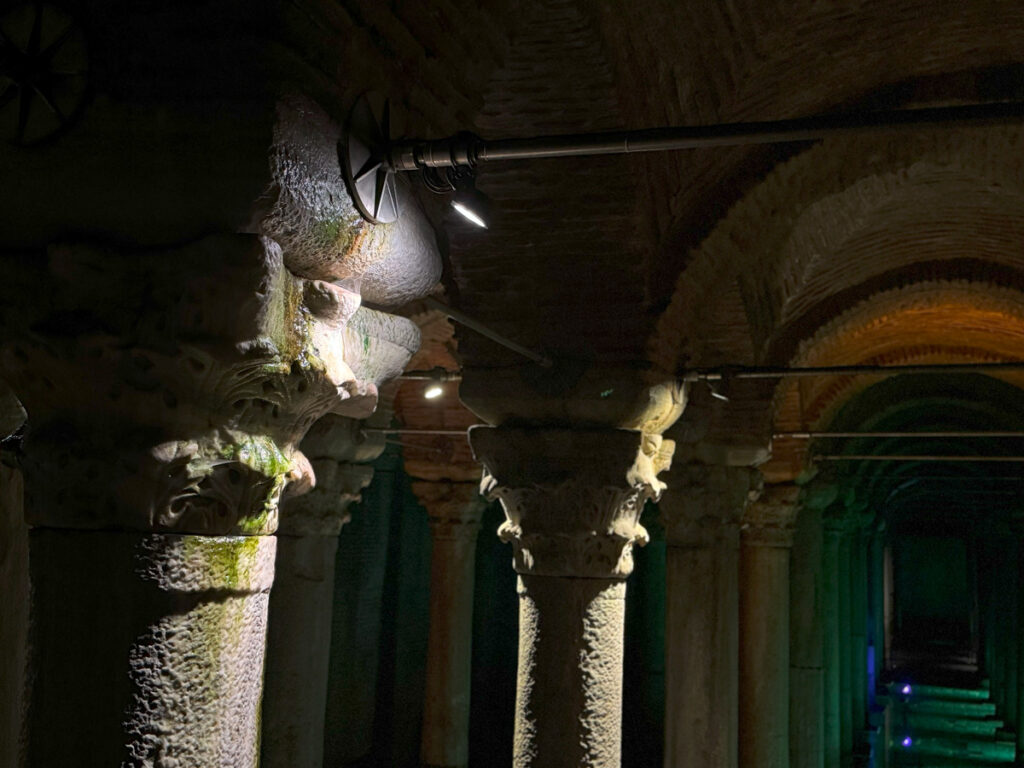 Close-up of the northern arch structures inside the Basilica Cistern, with intricately carved capitals illuminated under soft light.
