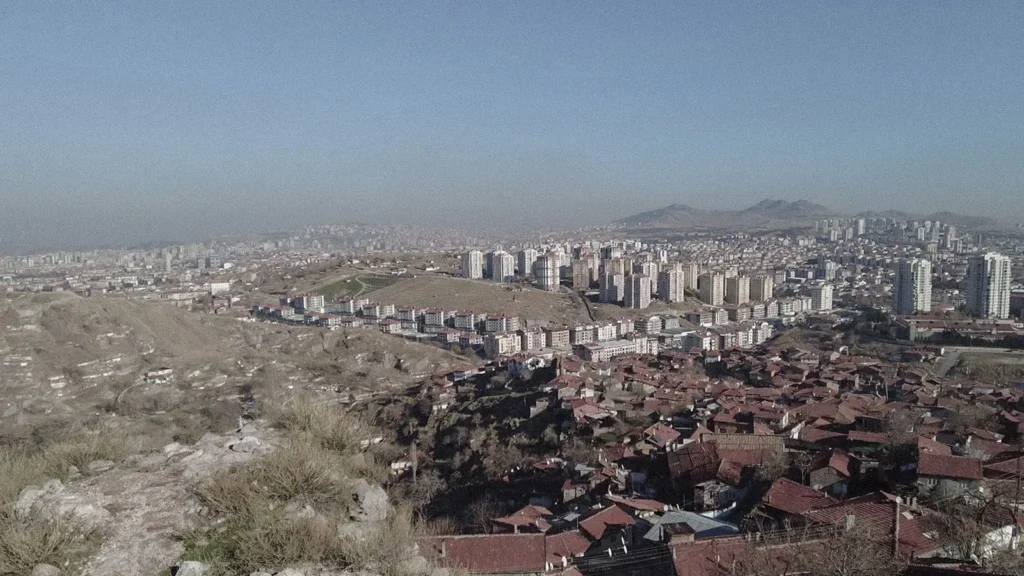 Wide view of Ankara from a dry hillside under a pale afternoon sky