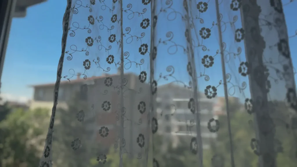 Thin lace curtain moving softly in an Ankara apartment window at morning