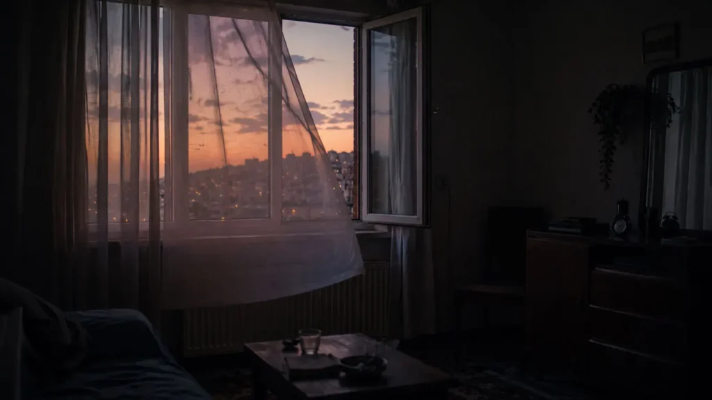 An open window with moving white curtains in a quiet Ankara apartment at dusk