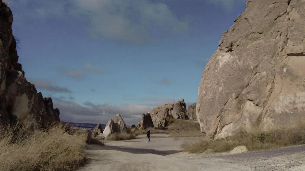 A solitary figure standing on a quiet path between rock formations in Cappadocia
