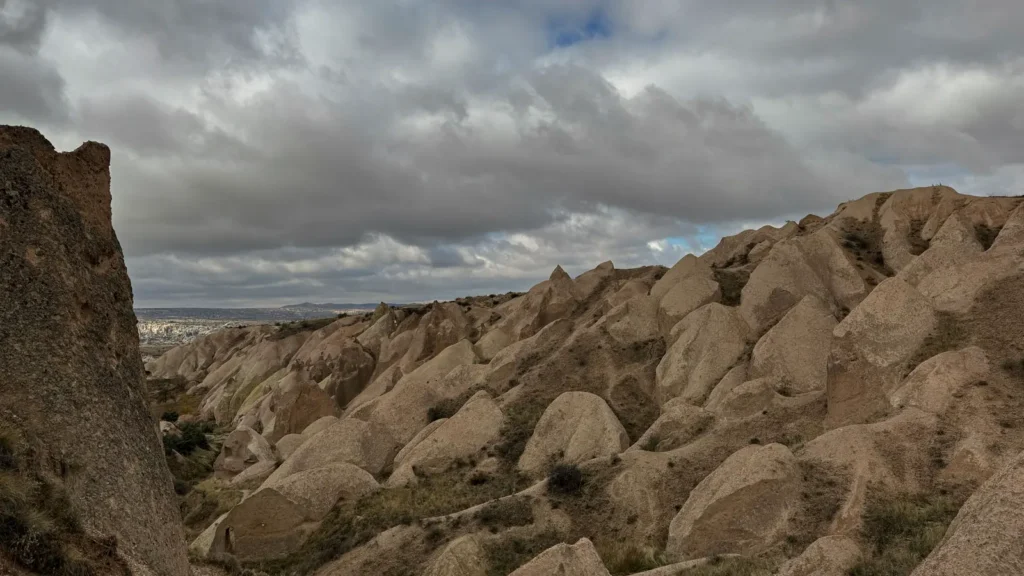 Rock formations in a quiet Cappadocia valley beneath a cloudy sky