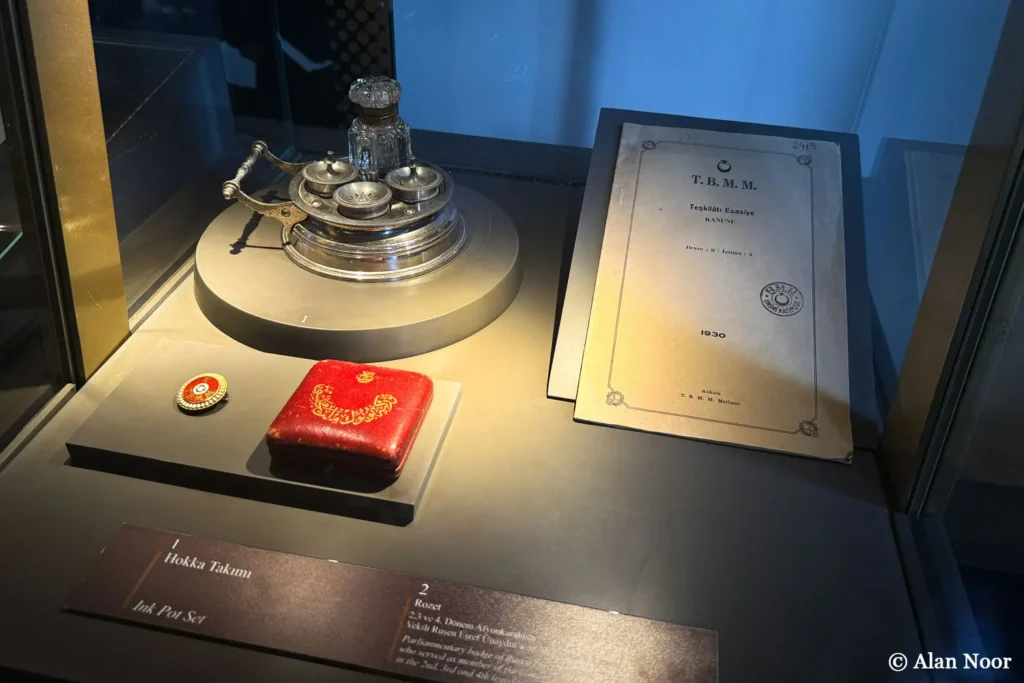 Museum display featuring a 1930 Teşkilâtı Esasiye Kanunu booklet, historic ink set, red case and rosette at Ankara Republic Museum.