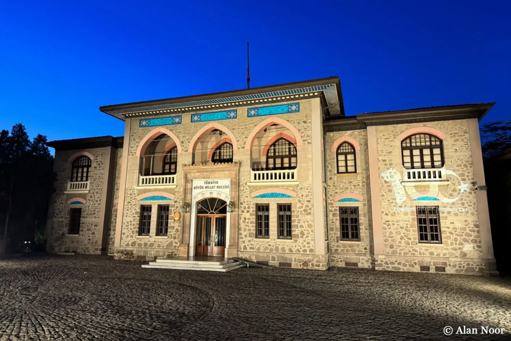 Republic Museum facade illuminated after dark beneath a blue evening sky in Ulus, Ankara, Türkiye.