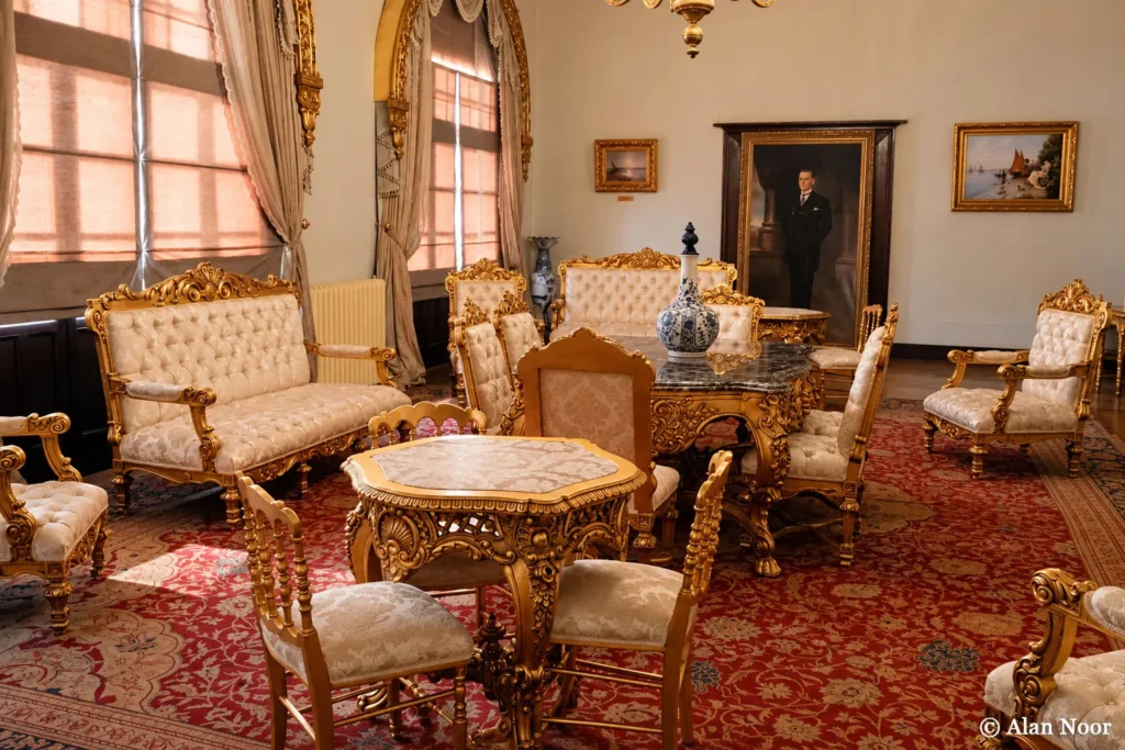 Gilded sofas, ornate chairs, decorative tables and a red patterned carpet in a historic reception room at Ankara Republic Museum.
