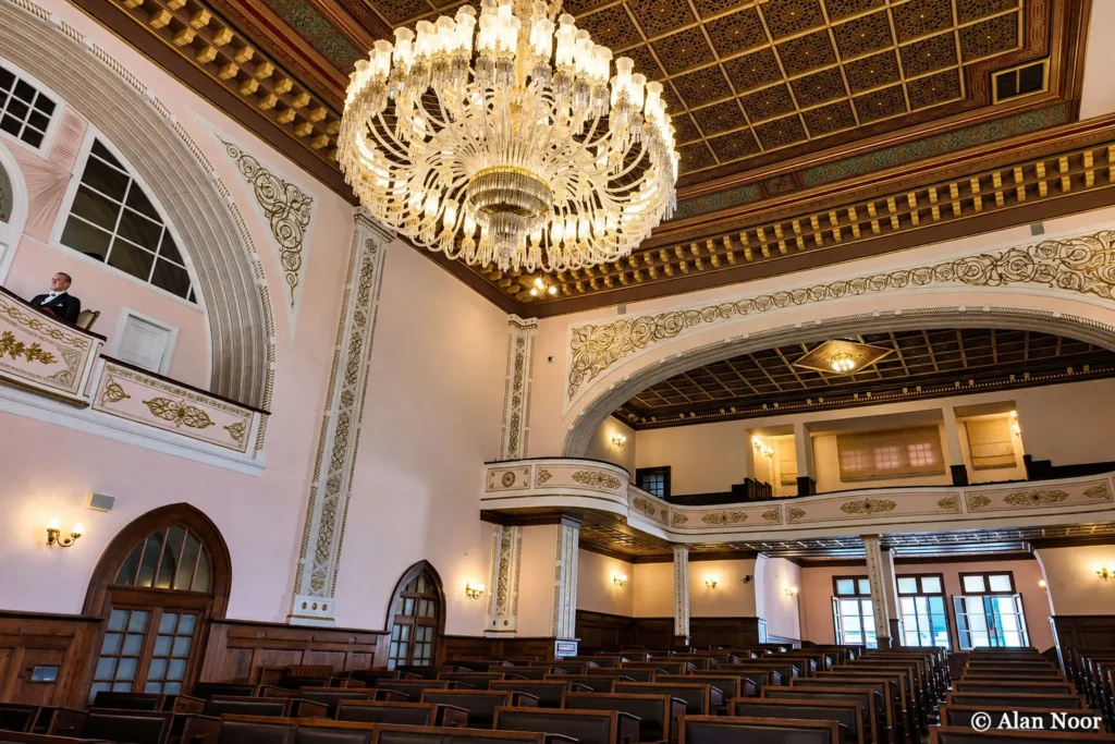 Historic parliamentary chamber at Ankara Republic Museum with wooden benches, upper galleries, ornate ceiling and a large chandelier.