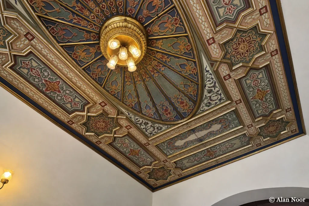 Close-up of an ornate painted ceiling with colorful floral and geometric patterns and a central light fixture inside Ankara Republic Museum.